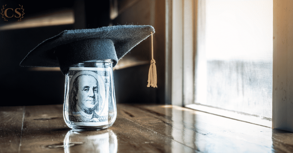 Dollar bill placed in a glass jar with a graduation cap on top