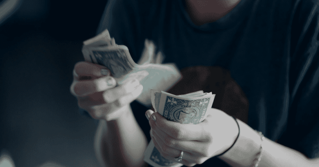 A person counting dollar bills.